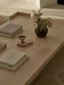 A cozy living area with a dining table, books, and a vase with flowers, creating a warm and inviting atmosphere