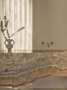 Bathroom with marble countertop, two sinks, and a vase with flowers, creating a luxurious atmosphere