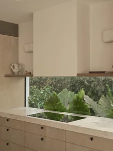 Open kitchen with a sink featuring a glass window for plants, surrounded by cabinets and a refrigerator, with two potted plants on either side