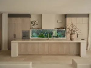 Open kitchen with a large aquarium on the countertop, potted plants, and two benches, set in a well-lit and inviting space