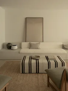 A cozy living room in a white house with a couch, chair, table, and decorative vases, creating a clean and inviting atmosphere
