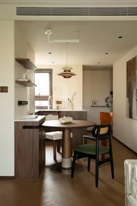 Cozy open kitchen space with wooden floors, white walls, and decorative elements such as potted plants, vases, and bottles