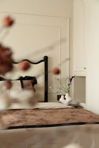 Cozy bedroom with a bed against a wall, vases, and a potted plant, creating a warm atmosphere