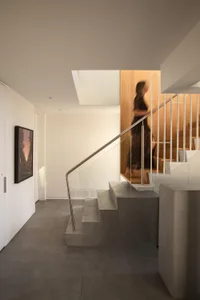 A woman walks up a wooden staircase in a calm and inviting interior space