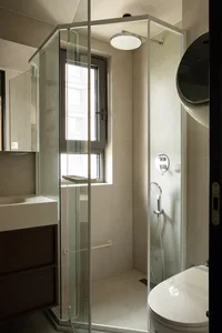 Bathroom with a modern glass shower stall, sink area, and natural light from a window