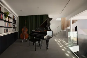 Cozy living space with a piano and books, featuring a black and gold piano and a warm atmosphere