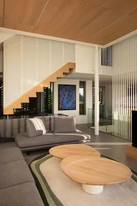 Cozy modern living space with a large couch, two chairs, a TV, and a staircase leading to another level