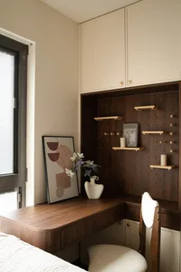 A cozy home office with a wooden desk, chair, vases with flowers, and a book, creating a warm and inviting atmosphere