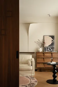 A well-lit living room with a couch near a doorway, featuring vases and a book on a table