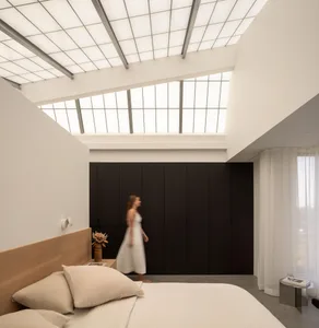 A calm and inviting bedroom with a large bed, white sheets, and a couch on the left side, two people are present in the room