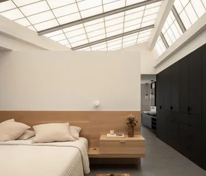 A well-organized bedroom with a large bed, white pillows, vases, and a book on a nightstand, creating a clean and inviting atmosphere