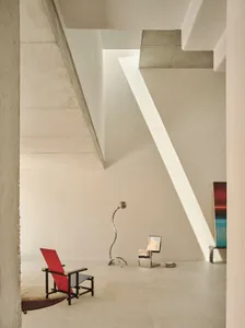 Bright and inviting living space with a red chair, dining table, and various furniture pieces, well lit by sunlight through windows