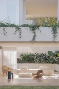 A warm and inviting living area with a white couch, chairs, and potted plants, decorated with vases and a cozy atmosphere