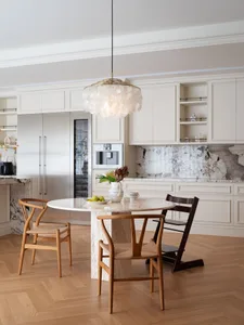 Warm and inviting kitchen with wooden floors, white cabinets, and a dining table with a bowl, chairs, and kitchen appliances
