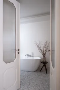 A clean and organized bathroom with a white bathtub, two vases, and a potted plant, emphasizing functionality and simplicity