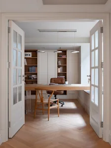 Cozy living space with a wooden floor, white walls, a large window, and furniture for reading and relaxation