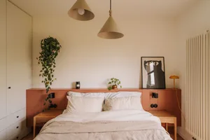 Cozy bedroom with a wooden platform bed, white bedding, and potted plants, with a warm and inviting atmosphere