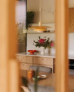 Warm kitchen with wooden cabinets and countertops, featuring a vase, bowl, cup, and potted plants, creating a cozy atmosphere