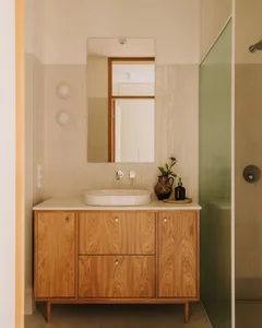 Modern bathroom with a sink and mirror above, two bottles on the countertop, and a shower area