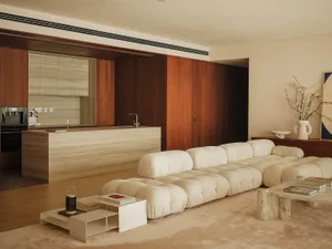 Open modern living space with a white couch, two sinks, and wooden walls, featuring clean lines and simplicity