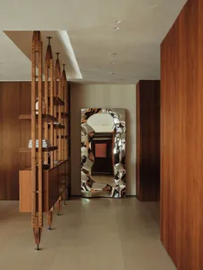 Warm and inviting living room with wooden floors and walls, large mirrors, and natural or artificial lighting