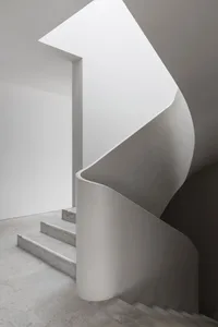 A gray concrete staircase with three steps leading upwards in a residential home, creating a sense of depth and structure