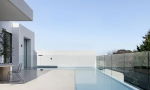 A serene indoor pool area with a glass wall offering a clear view of the empty pool, surrounded by chairs for relaxation and socializing