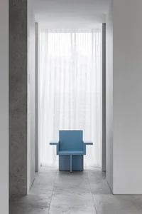 Empty room with a wooden chair and blue cushion in front of a window, surrounded by white walls and natural light