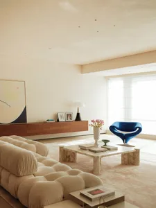 A modern living area with a white couch, chairs, dining table, and decorative vase, surrounded by clean lines and minimal decor