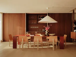 Warm and inviting dining area with a large wooden table, chairs, wine glasses, and bottles, perfect for social gatherings and meals
