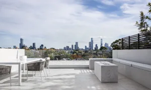 A modern living space with a glass wall offering a city skyline view, featuring two couches, a dining table, and a chair, with a stylish and functional interior design