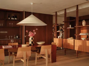 A modern dining room with a wooden table, chairs, wine glasses, and decorative vases, exuding comfort and luxury