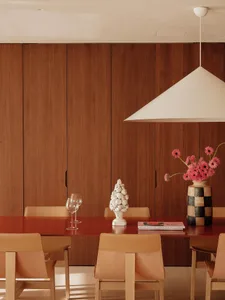 Dining area with a wooden table, chairs, wine glasses, and vases, creating a warm and inviting atmosphere