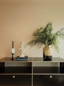 Cozy living space with a wooden table, vases, a plant, a book, and an egg, set in a warm and inviting atmosphere