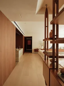 Open living space with wooden floors and walls, featuring two couches, a chair, and decorative vases, with natural light and ample seating