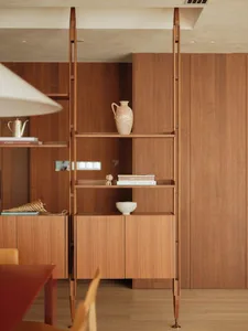 A modern study with wooden walls and floors, featuring two bookshelves filled with books, vases, and a bowl, creating a warm and inviting atmosphere