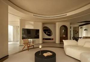 Cozy white bedroom with a round fireplace, two chairs, a TV, and a book, creating a relaxing atmosphere