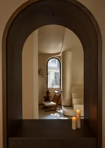 Cozy living space with a staircase, two chairs, a potted plant, and natural light from windows