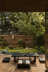 A relaxed outdoor dining space with a wooden table and metal chairs, surrounded by a patio area with a casual atmosphere