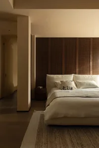 A well-lit bedroom with a large white bed, wooden headboard, and two pillows, set in a calm and inviting atmosphere