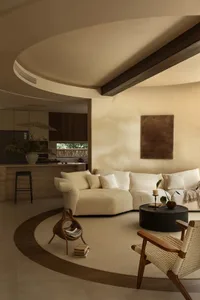 Open living area with white walls, beige furniture, and decorative elements, featuring a kitchen, dining area, and living room