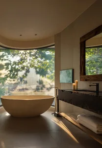 A serene bathroom with a white bathtub, candles, and a window, creating a peaceful ambiance