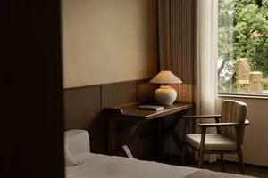 Cozy bedroom with a bed, chair, desk, and lamp, creating a warm and inviting atmosphere