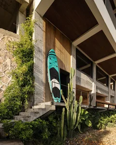 A modern building with a wooden surfboard leaning against its wall, set against a blank background