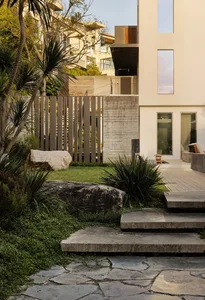 A modern house with a large white exterior wall, two sets of stairs, and a welcoming patio area