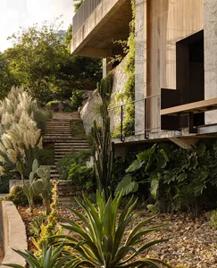 A house with a stone exterior, a large patio area, a staircase, and potted plants, creating a relaxed and inviting atmosphere