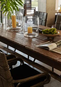 Warm and inviting dining area with a wooden table, chairs, vases, and a centerpiece of grapes