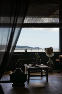 Cozy dining space with a table, chairs, couch, and ocean view, decorated with vases, plants, and a bowl, providing a relaxing atmosphere