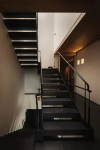 A residential staircase with wooden steps and black railings, featuring a calm and inviting atmosphere with a cat sitting at the bottom