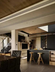 Open living area with wooden floors and walls, featuring a couch, chairs, vases, and a potted plant, with a warm and inviting atmosphere
